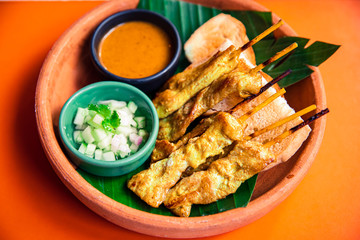 Grilled pork satay with peanut sauce and cucumber and onions in vinegar, Thailand street food