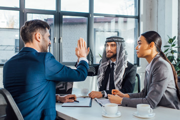 positive multicultural business partners giving highfive on meeting with translator in office