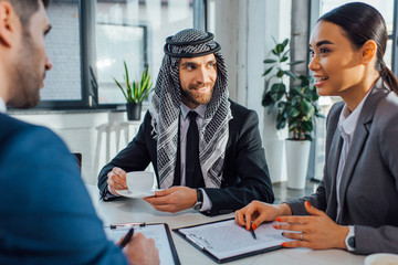 happy multiethnic business partners on meeting with translator in office