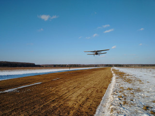 Fototapeta na wymiar Takeoff of an old biplane plane from a winter airfield from a runway with grass with a blue sky background