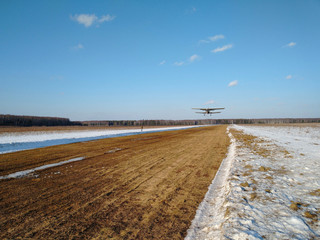 Takeoff of an old biplane plane from a winter airfield from a runway with grass with a blue sky...