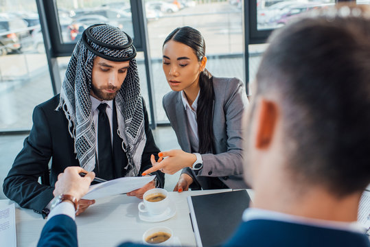 Multicultural business partners discussing contract on meeting with translator in office