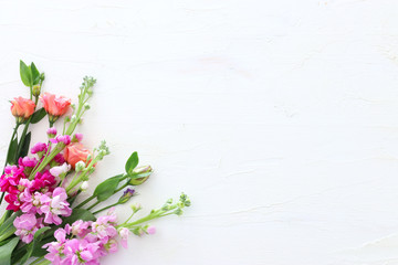 spring bouquet of pink flowers over white vintage wooden background. top view, flat lay