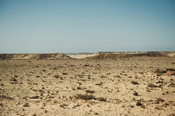 extreme adventures or science expedition in a stone desert. Sahara desert at sunrise - mountain landscape with dust on skyline, hills and traces of the off-road car.