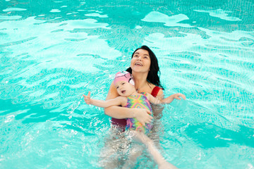 baby girl enjoying swimming in a pool, swimming lesson of young children in the pool, learning to swim in the childrens pool, early childhood development