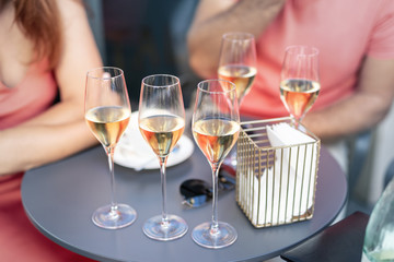 Close-up detail table with many filled glasses of white champagne prosecco at party celebration event outdoors. People having fun enjoy drink alcohol toasting cheers at cafe restaurant on summer day