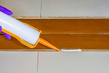 Technician man hand using glue gun with silicone adhesive or manual caulking gun with polyurethane...