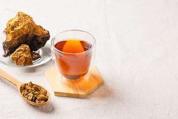 Healing tea from chaga birch mushrooms in a glass cup. Organic drink antioxidant . The concept of...