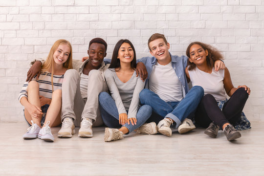 Happy students posing over white brick wall