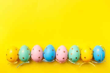 Fototapeta na wymiar Easter colored eggs border on yellow background. Happy Easter greeting card minimal concept. Top view, flat lay, copy space.