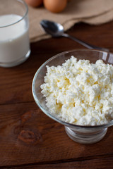 Homemade rustic crumbly cottage cheese with milk on a wooden background. Still-life.