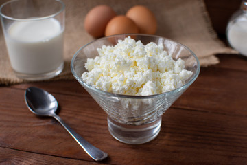 Homemade rustic crumbly cottage cheese with milk on a wooden background. Still-life.