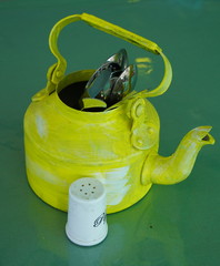 Kitchen utensils and cutlery in old fashioned green vintage teapot in bucket on table along with...