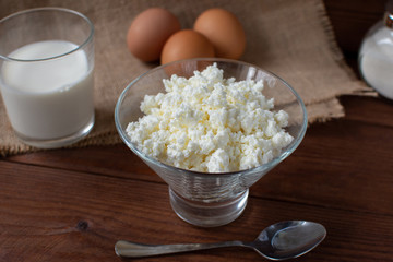 Homemade rustic crumbly cottage cheese with milk on a wooden background. Still-life.