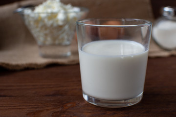 Homemade rustic crumbly cottage cheese with milk on a wooden background. Still-life.