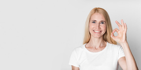 Happy mature woman gesturing okay sign and smiling