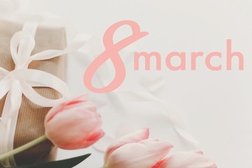 8 march. Happy womens day greeting card. 8 march text on pink tulips and gift box with ribbon on white background. Stylish tender image. Handwritten text, lettering