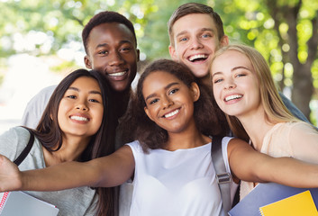 Cheerful group of friends taking selfie while walking in park