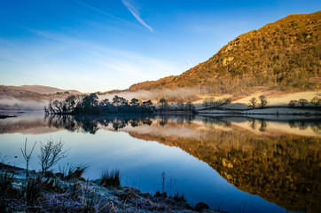 Early morning reflections on the lake at Rydal in the Lake District Cumbria showing the mist hovering over the water. 