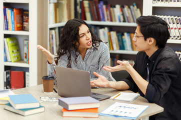 Multicultural couple sharing ideas about coursework in library