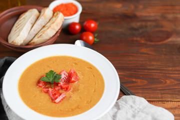 Vegetable soup with lentils on a wooden background. Served with chopped cherry tomatoes. Nearby are pieces of ciabatta. Raw groats in the background. Vegetarian dish.