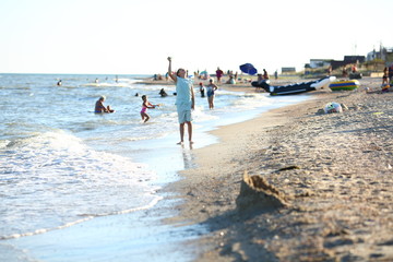 handsome boy in shorts and a t-shirt teenager launches a kite on the sky on the seashore in summer