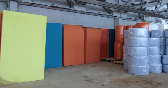 In huge warehouse, paralon in cubes and rolls, synthetic materials for production of hygiene products and mattresses, multi-colored raw materials, sponges, production, spacious and dry warehouse