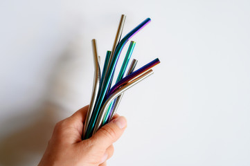 several reusable metal stainless steel drinking straws in female hand on a white background