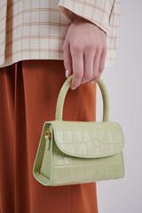 Beautiful leather green handbag in girl's hand. Luxury handmade bag with reptile effect....