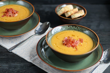 Lentil soup on a wooden background. Served with sliced bacon and herbs. Nearby are pieces of ciabatta. Raw groats in the background.