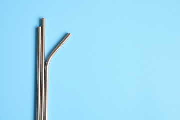 reusable metal stainless steel drinking straws on a blue background. space for text