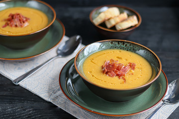 Lentil soup on a wooden background. Served with sliced bacon and herbs. Nearby are pieces of ciabatta. Raw groats in the background.