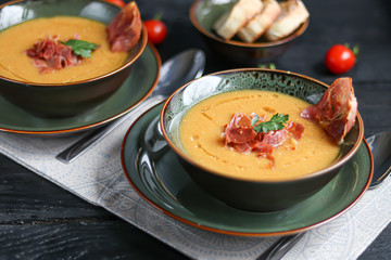 Lentil soup on a wooden background. Served with sliced bacon and herbs. Nearby are pieces of ciabatta. Raw groats in the background.