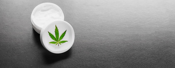 Jar with hemp lotion, cannabis cream with hemp leaf with dark copy space. Natural product, cosmetic...