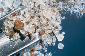 Fototapeta premium a metal shovel gains raw crystals with a black splash in macro shot on a dark background
