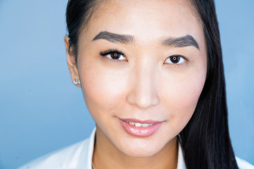 Portrait of a beautiful asian woman during eyelash extension procedure. Double eyelash volume before and after.