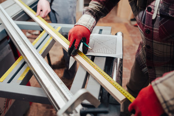 Worker marks with pencil a plywood for cutting on a circular saw