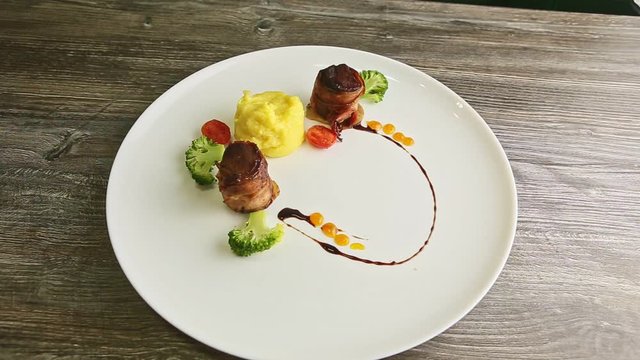 top view at trandy decorated meat pieces roasted in bacon with puree