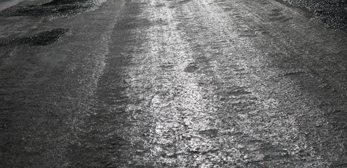 Icy road. Selective focus. Hazard concept ice-crusted ground. Black and white image.