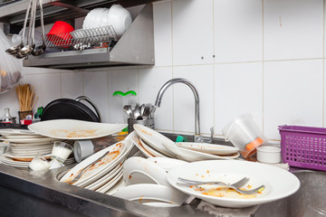 Metal sink full of dirty dishes, crockery, tableware