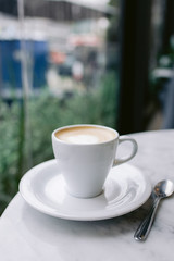 One cappuccino on a white table in a coffee shop