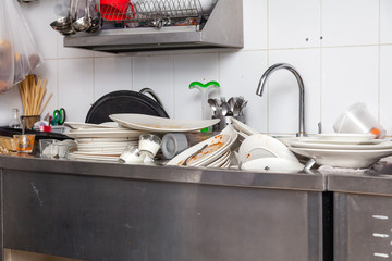 Metal sink full of dirty dishes, crockery, tableware