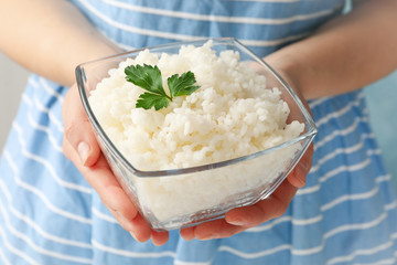 Woman holding bowl with delicious rice, close up