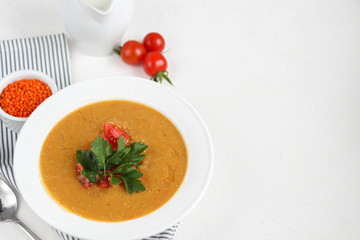 Vegetable soup with lentils on a white background. Served with chopped cherry tomatoes and herbs. Nearby are pieces of ciabatta. Raw groats in the background. Vegetarian dish.
