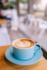 One cappuccino on a wooden table at a coffee shop