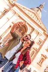 A happy couple taking a selfie in front of a historic landmark