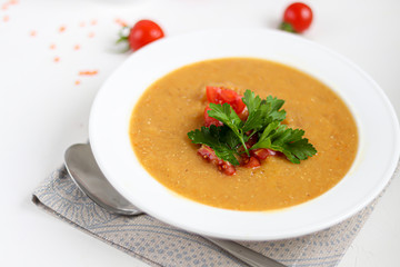 Vegetable soup with lentils on a white background. Served with chopped cherry tomatoes and herbs. Nearby are pieces of ciabatta. Raw groats in the background. Vegetarian dish.
