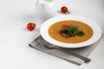 Vegetable soup with lentils on a white background. Served with chopped cherry tomatoes and herbs. Nearby are pieces of ciabatta. Raw groats in the background. Vegetarian dish.