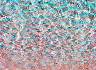 Transparent ripple water texture in a summer sea, ocean or swimming pool. Clear shiny textured surface under sunlight.