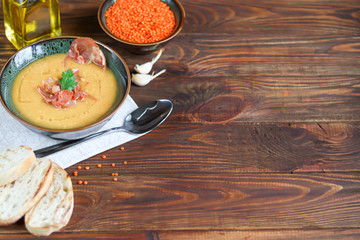 Vegetable soup with lentils on a wooden background. Served with chopped cherry tomatoes and herbs....